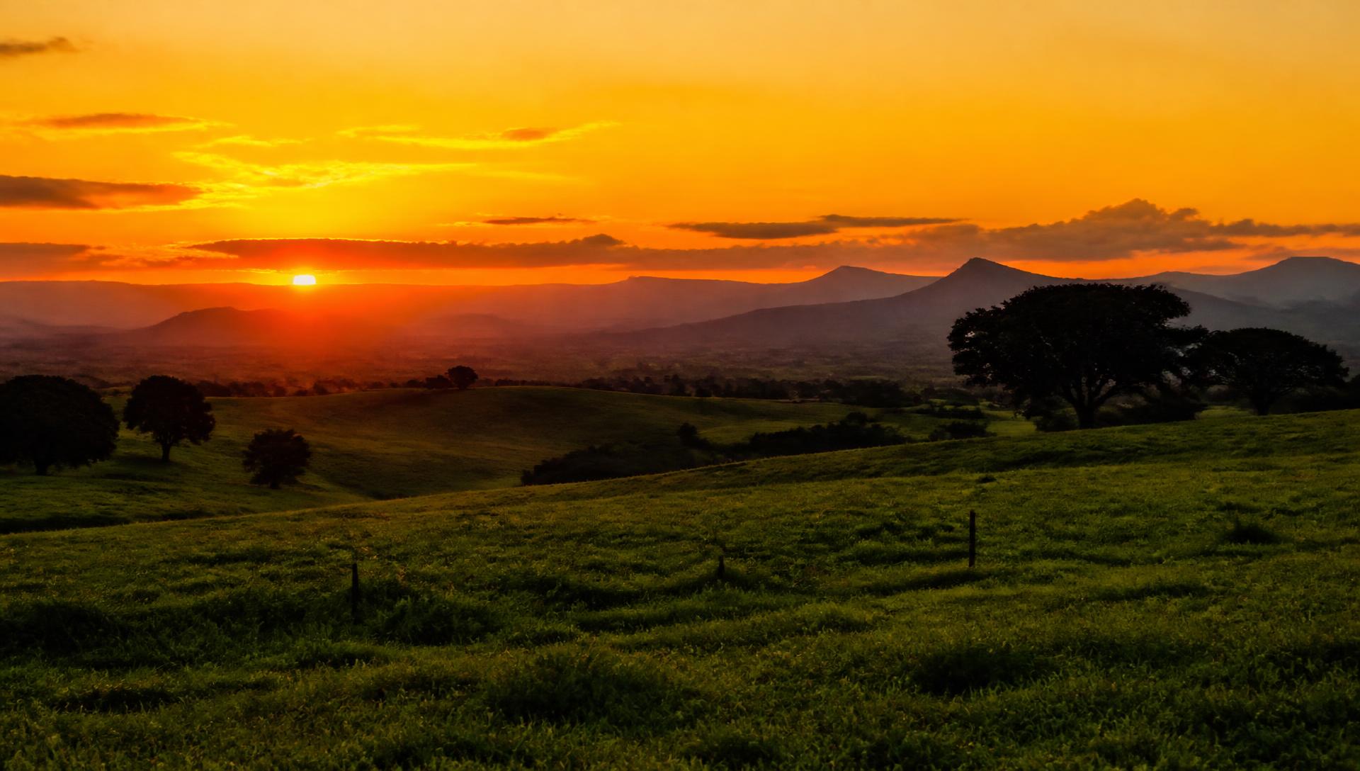 Pôr do sol sobre campo e serra